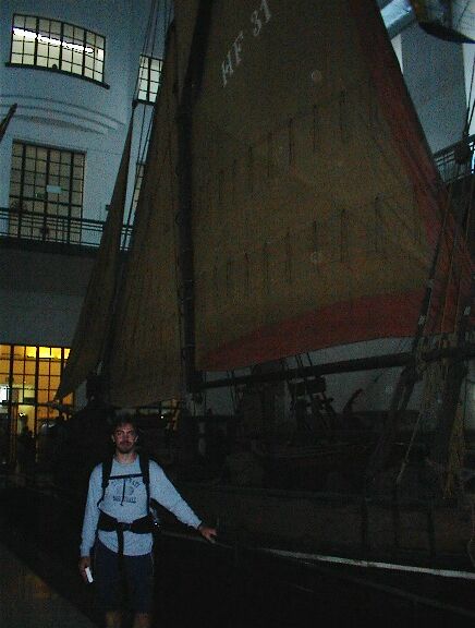 Roger by a large boat in the museum (poor lighting)